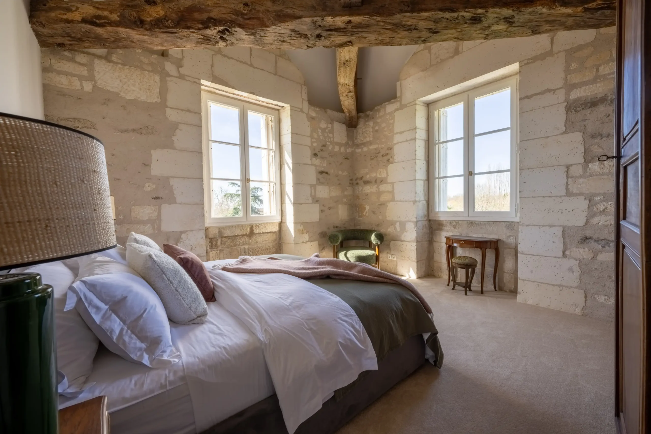 Luxurious living space with red sofas, gold mirror, and large windows in a French castle