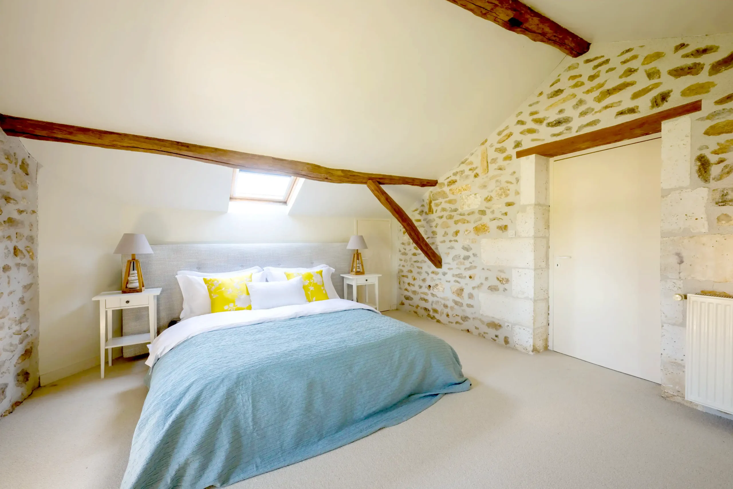 Bright attic bedroom with wooden beams and a double bed