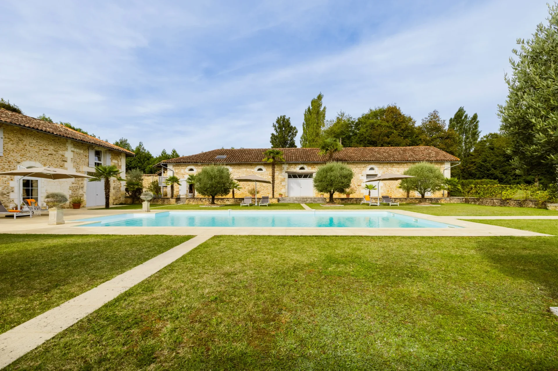 Outdoor pool with lawn and trees in the background
