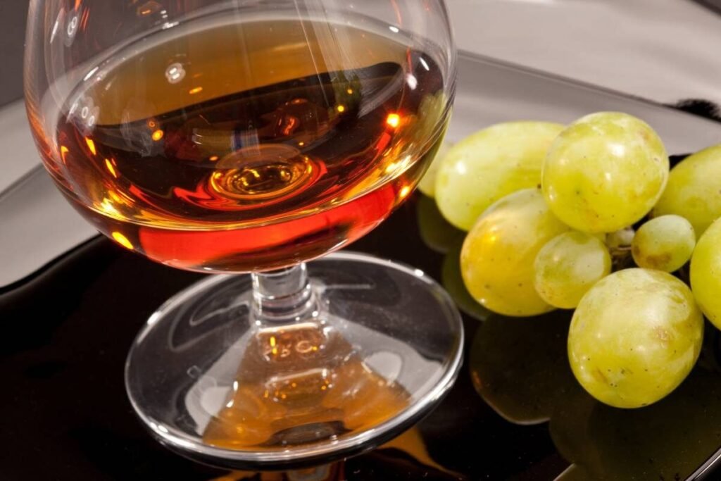 cognac vs brandy. a glass of cognac with a bunch of grapes
